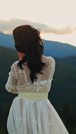 beautiful female model on green landscapes. pretty woman in white dress walking in the mountains. vertical video