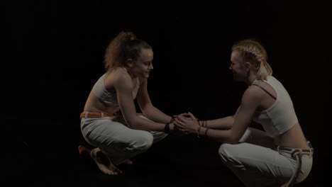 group of a professional dancers are practicing capoeira in darkness against a spotlight on a black background of studio. afro-brazilian martial art that combine elements of dance.