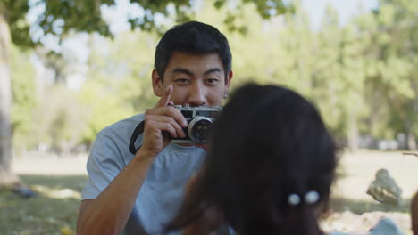 smiling asian man taking photo of little daughter with camera