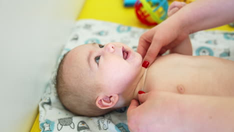 pediatrician's hands touching and checking baby's neck. little kid opens mouth sweetly and looks curiously at the doctor. close up.