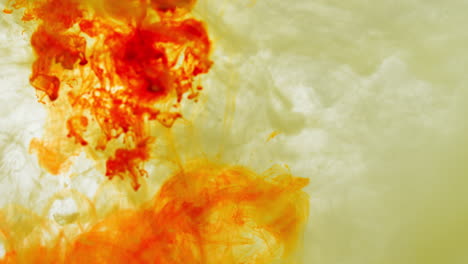 yellow and orange paint or dye dropped into water against white background to create swirling colourful smoke background 1