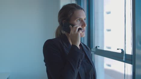 serious pensive young businesswoman standing near window