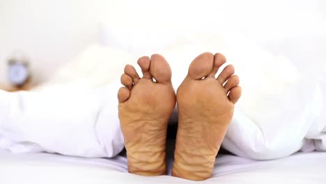 man wiggling his toes under the covers