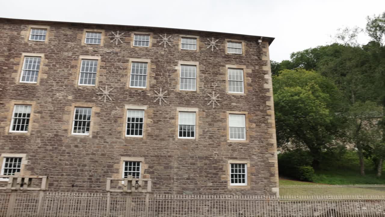 Slow establishing shot of antique buildings within New Lanark