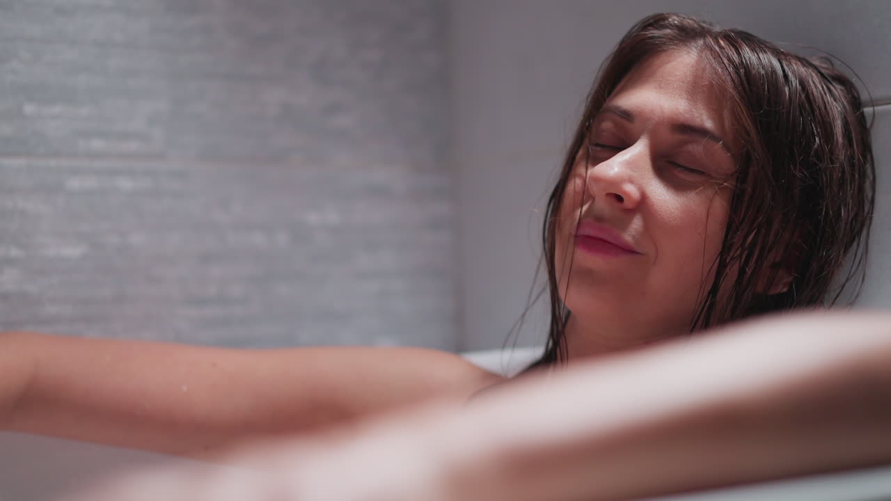 집에서 뜨거운 욕조에 누워있는 여자가 미소 짓고 있습니다. 은 머리카락을 가진 예쁜 여자는 욕실에서 스파 절차 중에 휴식을 즐니다. 여성은 힘든 하루 후에 휴식을 취합니다.