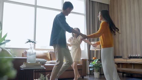 happiness sunday morning dad mom and daughter spending wonderful moment dancing along together,asian family father mother and daughter jump dance cheerful moving together in living room at home