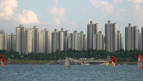 Zwei-Windsurfer,-Die-Bei-Sonnenuntergang-Schnell-über-Den-Fluss-Han-Surfen,-Jamsil-Apartment-Im-Hintergrund,-Schöne-Pinky-Wolken-Seoul,-Südkorea