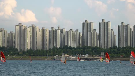 dos windsurfistas navegando rápidamente por el río han al atardecer, apartamento jamsil en el fondo, hermosas nubes rosadas seúl, corea del sur