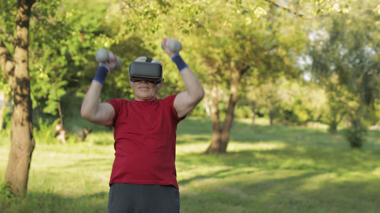 vr 헤드 헬을 입은 노인 할아버지 남자가 공원에서 덤벨로 피트니스 운동을 하고 있습니다.