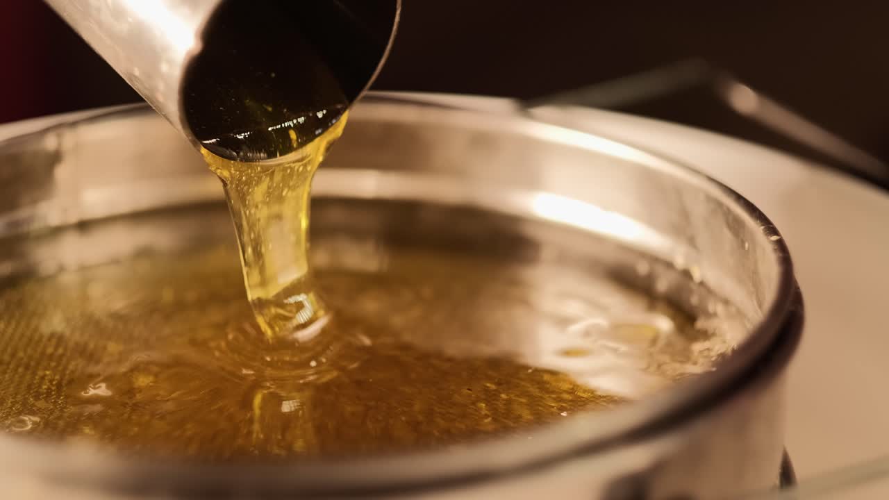 Primo piano di miele liquido naturale durante il processo di estrazione.