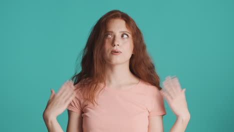 은 머리의 소녀가 르키즈색 배경에서 카메라를 보고 있습니다.