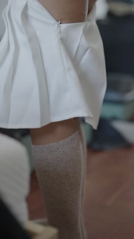 woman putting on white mini skirt