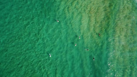 Drohnenschwenk-Aus-Der-Luft-Auf-Den-Pazifischen-Ozean-Mit-Surfern,-Die-Auf-Wellen-Auf-Der-Sandbank-North-Avoca-Beach,-NSW,-Australien,-4k-Warten