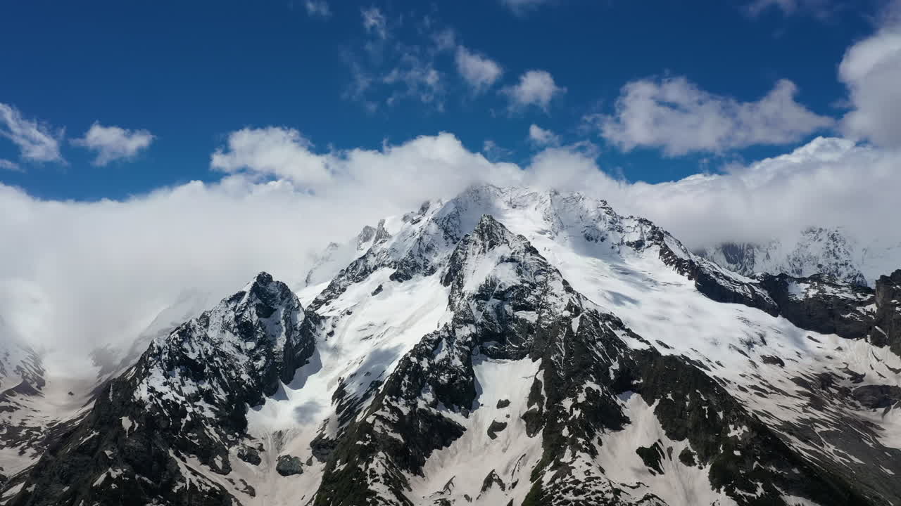 vuelo aéreo a través de nubes montañosas sobre hermosos picos nevados de montañas y glaciares.