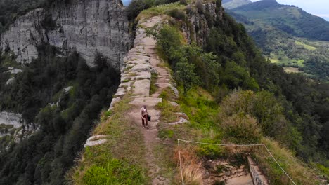 Aerial:-zenital-shot-of-a-man-with-a-suitcase-walking-on-a-clif