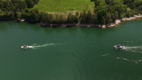 Sideways-aerial-shot-of-two-leisure-motor-boats-navigating-Beaver-lake,-summer