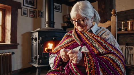 ältere frau, die am kamin strickt