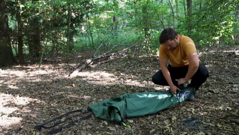 Adulto-Joven-Rueda-Y-Pone-La-Carpa-En-La-Bolsa-Después-De-La-Noche-De-Campamento-En-El-Bosque