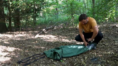 adulto joven rueda y pone la carpa en la bolsa después de la noche de campamento en el bosque