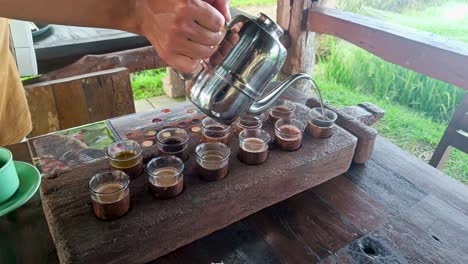 vista lateral hombre mano vertiendo luwak balí café con mesa de madera y vaso de taza verde sintiéndose feliz y lleno de energía por la mañana