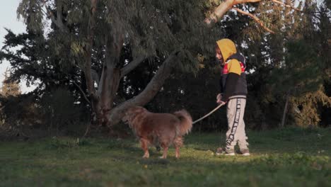 Vista-Trasera-De-Un-Niño-Caucásico-Caminando-Con-Su-Perro-Mascota-Con-Una-Correa-En-El-Bosque-Cerca-De-La-Montaña-Parnitha,-Grecia