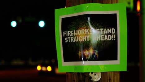 fireworks stand straight ahead green home made small business sign posted stapled to telephone pole at night with car lights bokeh in background as camera dolly pans left