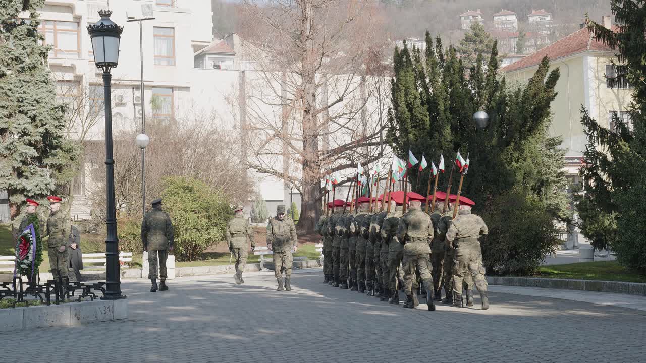 Ranks of soldiers at memorial parade march off with national flag attached to rifles