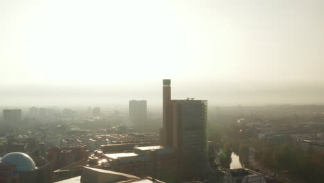 Fly-towards-tall-building-in-town-on-river-bank.-Romantic-morning-hazy-view-against-sun.-Berlin,-Germany