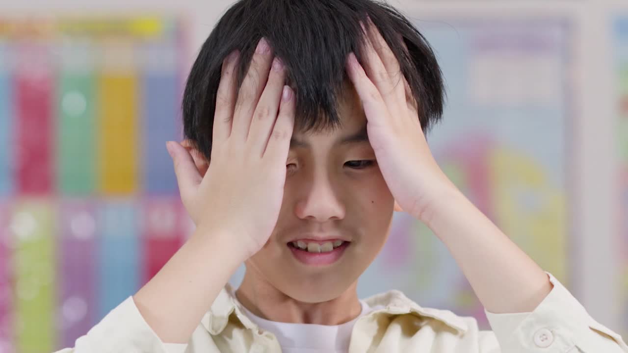 頭を強く押さえながら、頭痛とストレスの兆候を見せる若い学生