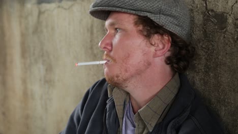 profile shot of a homeless young adult male lighting and smoking a cigarette in despair