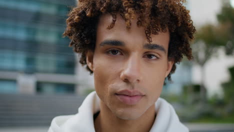 Young-man-looking-camera-in-downtown-closeup.-Smiling-latin-guy-posing-portrait