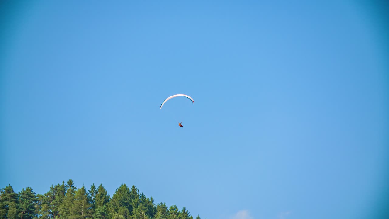 파란 하늘 배경 속에서 하늘 높이 패러글라이더가 움직이고 있어요.