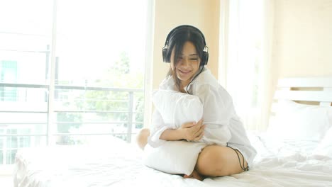 young asian women listening music on bed.
