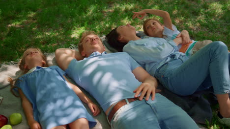 happy family relax lying on picnic blanket close up. people rest on green lawn.