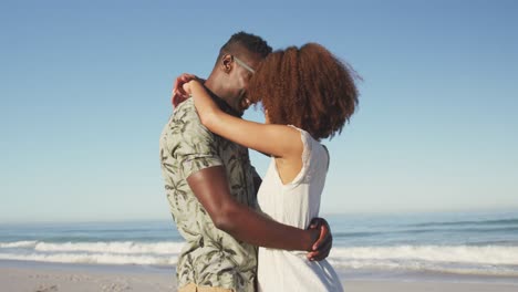 pareja afroamericana acurrucada en la playa