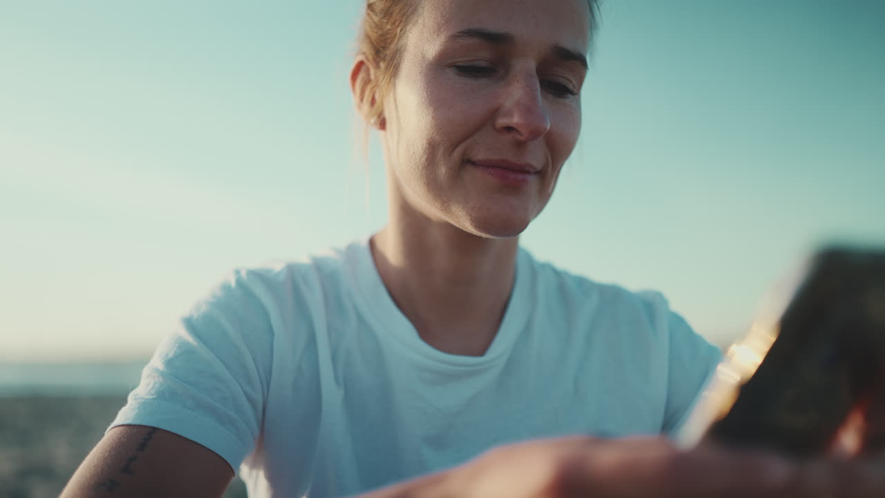 Sportswoman sitting using her smartphone on the beach.