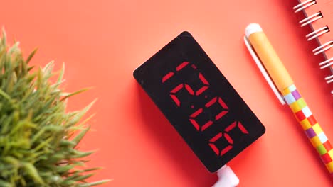 digital clock and office supplies on coral desk