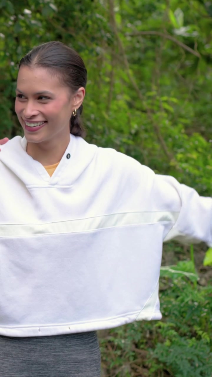 Video verticale: Donna con felpa con cappuccio che si allunga muovendo le braccia su un sentiero, un amico le posa una mano sulla spalla.