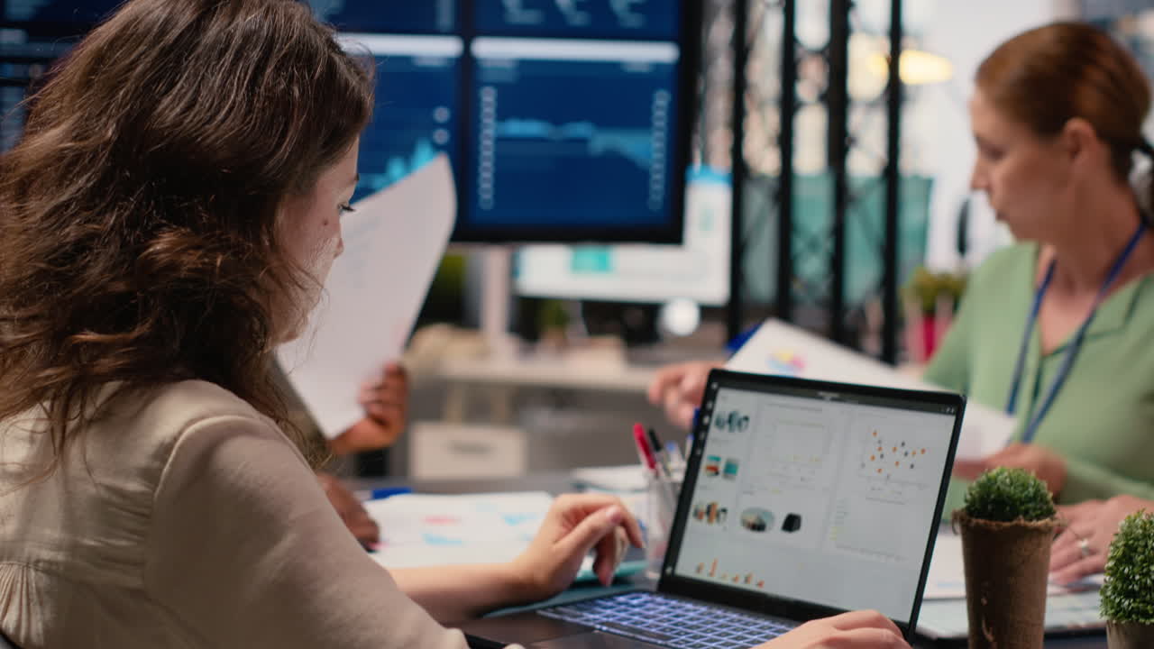 Focused businesswoman analyzing graphs and data on laptop at the table