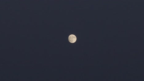 filming with a drone at night in 167mm of the moon in its full moon state, the entire background is dark and on the moon we can see its largest spots, it moves from right to left, in slow motion