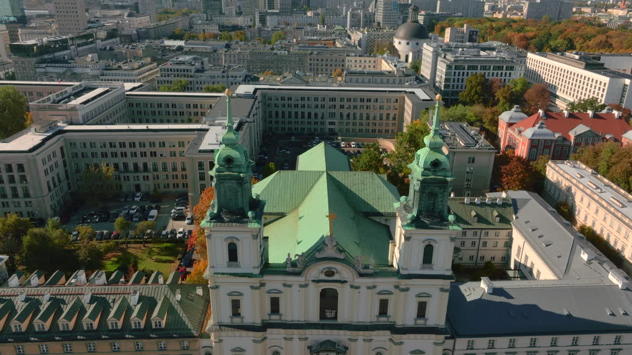 Revealing panoramic aerial shot of Warsaw city's modern skyscrapers flying over Holy Cross catholic church in older part of city center