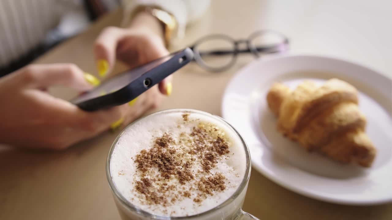 Woman enjoying breakfast and working on her smartphone