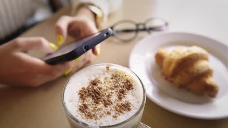 woman enjoying breakfast and working on her smartphone