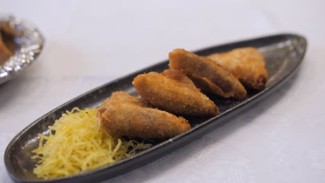 unique shape of spanish croquetas served with grated cheese on the side