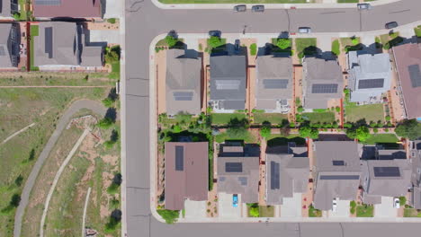 medium overhead aerial view of suburban neighborhood in the summer with renewable and green rooftop solar panels to help the climate