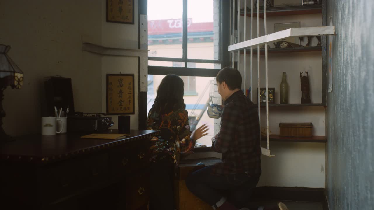 Couple waters plants at home and laughs.