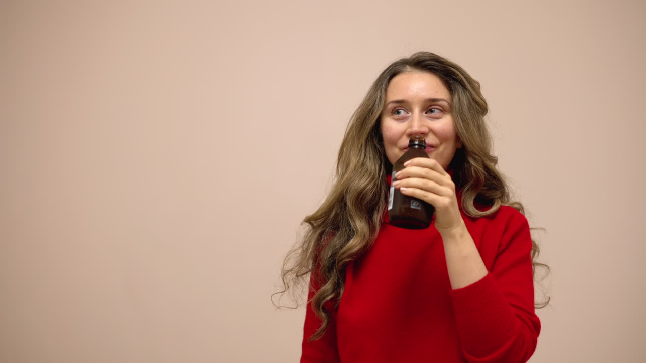 Woman drinking kombucha from a brown glass bottle