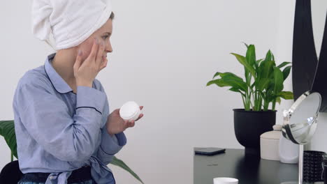 mujer joven aplicando crema hidratante