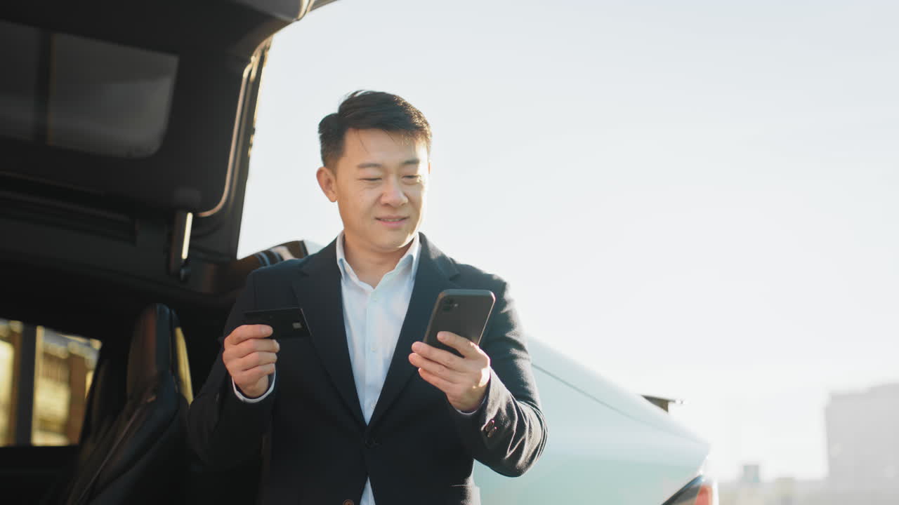 スマートフォンで電気自動車の充電を支払う男性