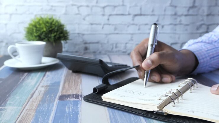 Person writing in a planner at a desk